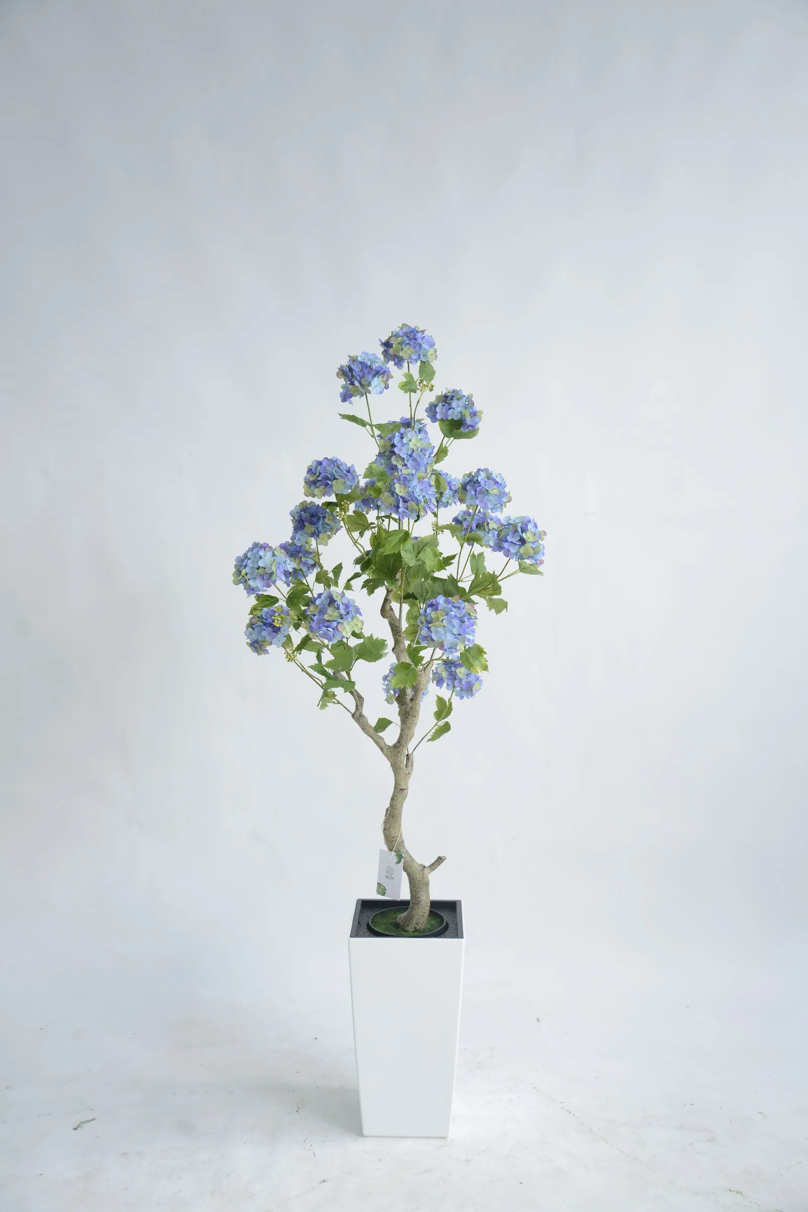 Artificial blue hydrangea potted arrangement with natural wood trunk